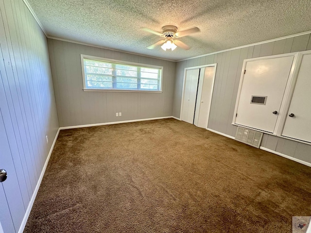 unfurnished bedroom featuring a textured ceiling, ceiling fan, and dark colored carpet