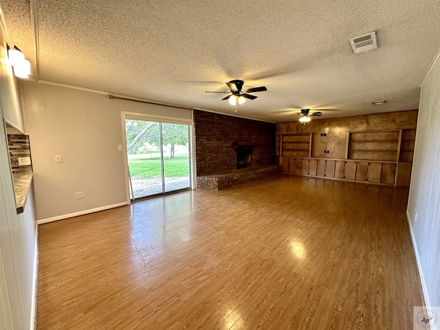 unfurnished living room featuring a brick fireplace, a textured ceiling, hardwood / wood-style floors, and ceiling fan