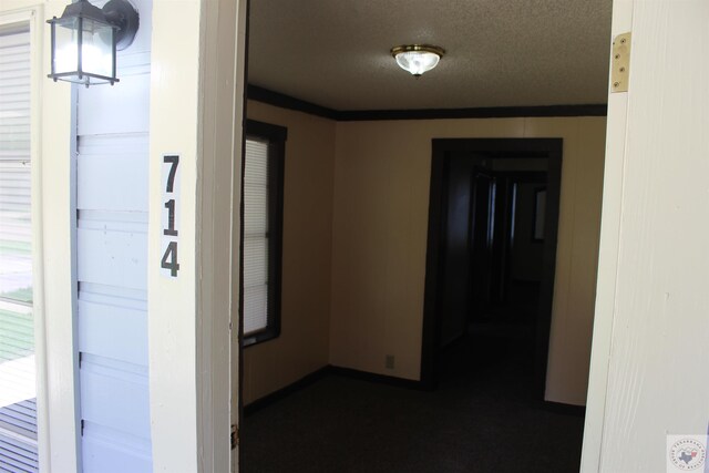 corridor featuring a textured ceiling and ornamental molding