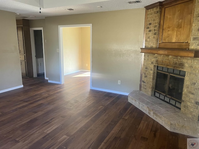 unfurnished living room with a textured ceiling, dark hardwood / wood-style floors, and a brick fireplace