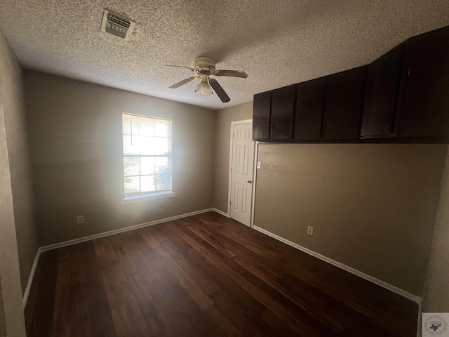 unfurnished room featuring ceiling fan, dark hardwood / wood-style floors, and a textured ceiling