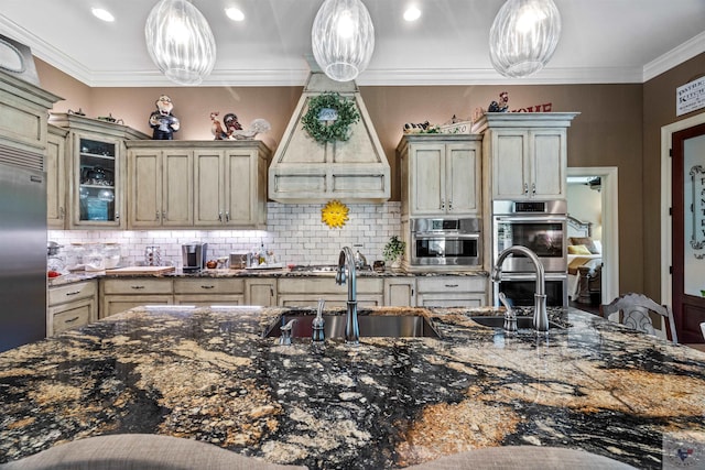 kitchen with decorative light fixtures, backsplash, stainless steel appliances, and cream cabinets