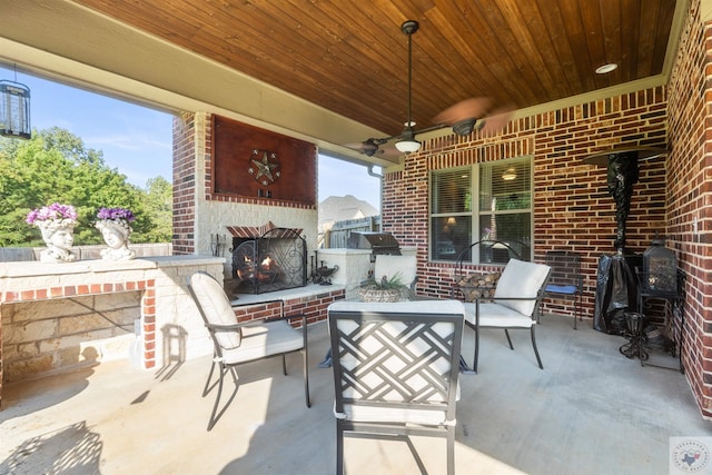 view of patio / terrace featuring ceiling fan, a bar, and an outdoor brick fireplace