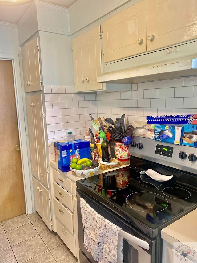 kitchen featuring stainless steel electric stove, light tile patterned floors, backsplash, and white cabinets