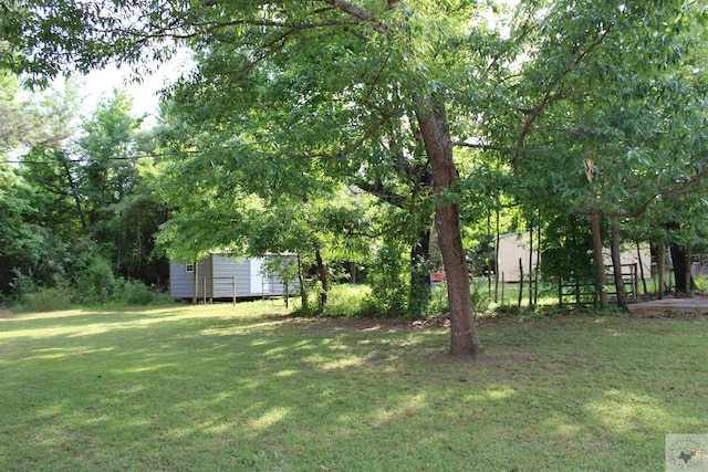 view of yard with fence, a storage unit, and an outdoor structure