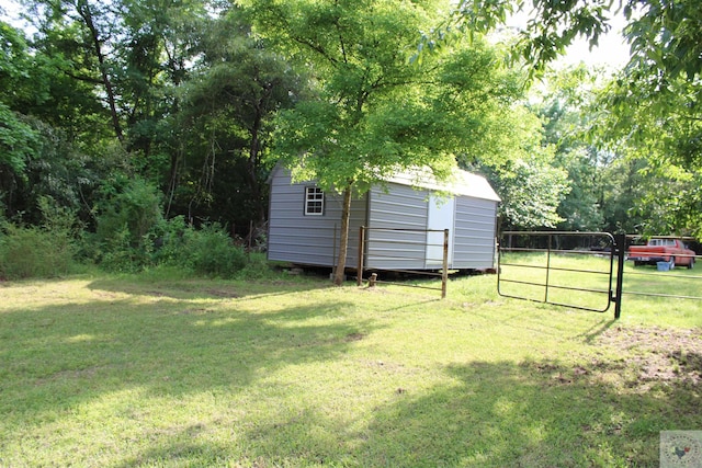 view of yard with an outbuilding, a gate, fence, and a storage unit