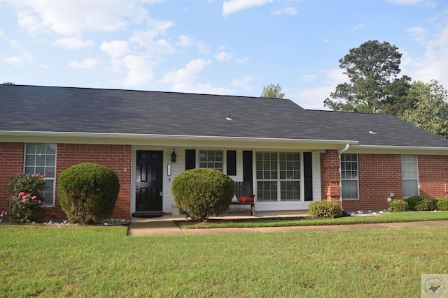 ranch-style home with brick siding, covered porch, and a front yard