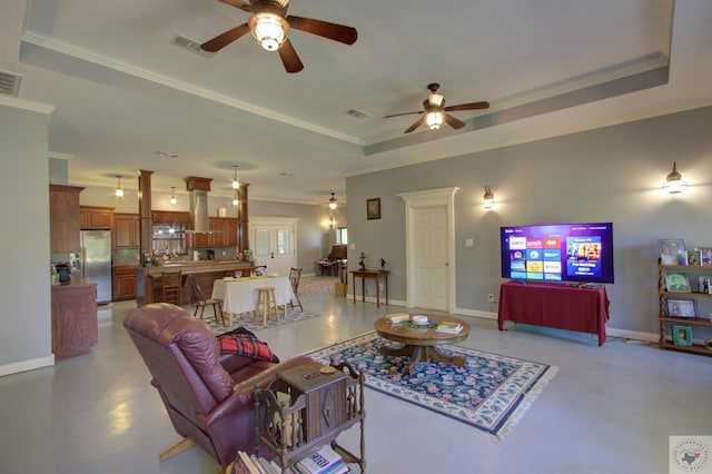 living room with ceiling fan, a tray ceiling, and ornamental molding