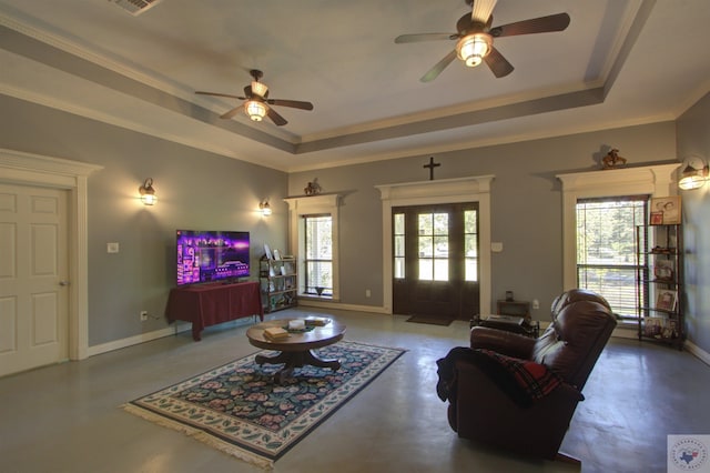 living room with ceiling fan, ornamental molding, concrete flooring, and a tray ceiling