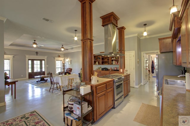 kitchen with hanging light fixtures, ornate columns, a tray ceiling, stainless steel gas range oven, and ornamental molding