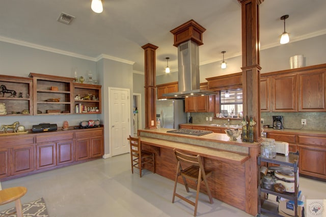 kitchen with appliances with stainless steel finishes, sink, hanging light fixtures, island range hood, and decorative columns