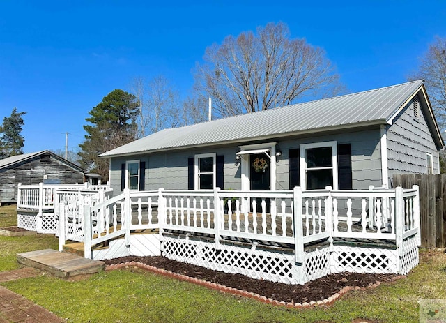 view of front of home featuring metal roof, a front lawn, and a wooden deck