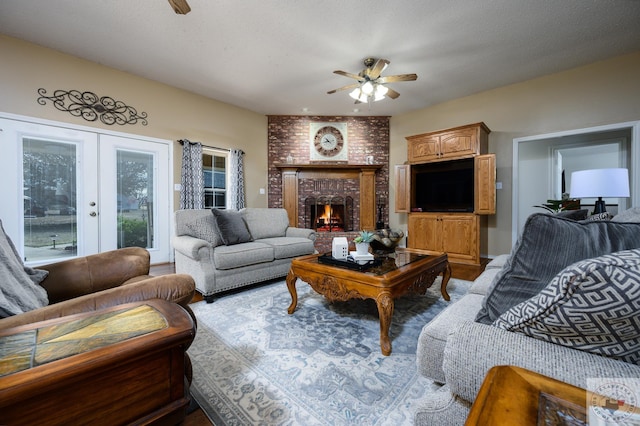 living area featuring a fireplace, french doors, and a ceiling fan