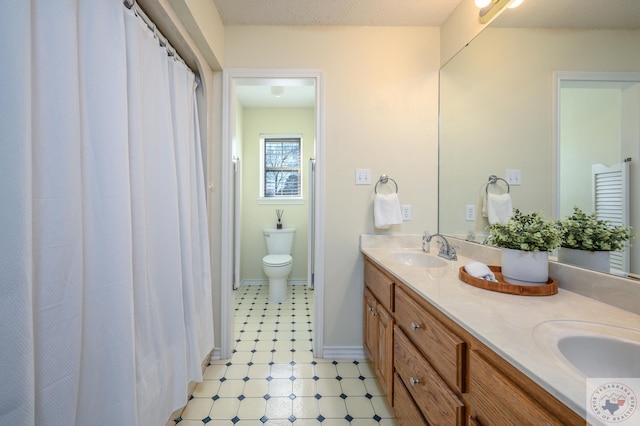 full bath featuring double vanity, toilet, baseboards, and a sink