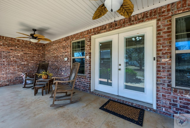 view of exterior entry featuring french doors, a patio, brick siding, and a ceiling fan