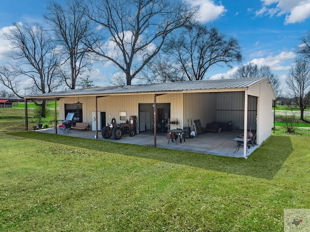 rear view of property featuring an outbuilding, a pole building, a garage, a lawn, and metal roof