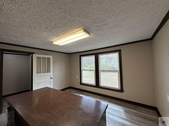 interior space with hardwood / wood-style floors, a textured ceiling, and ornamental molding