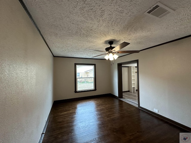 spare room featuring ceiling fan, dark wood-type flooring, a textured ceiling, and crown molding