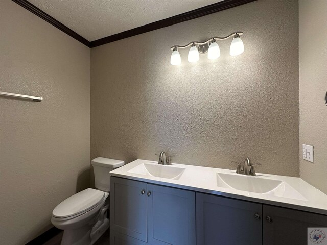 bathroom featuring a textured ceiling, toilet, vanity, and crown molding