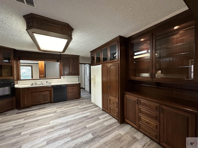 kitchen with dark brown cabinets, sink, light wood-type flooring, a textured ceiling, and black appliances