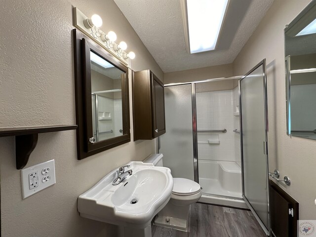 bathroom with sink, hardwood / wood-style flooring, a textured ceiling, and an enclosed shower