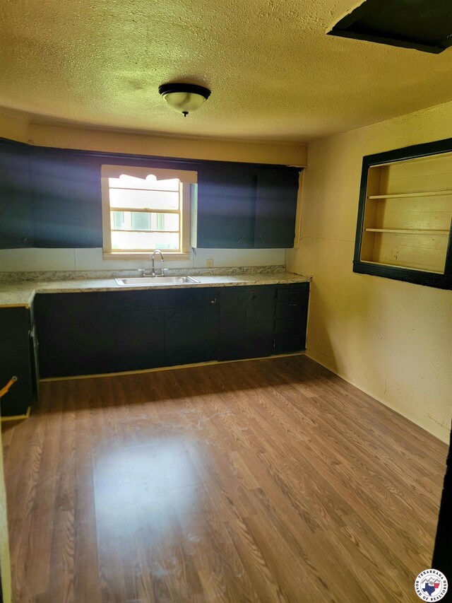 501 S Columbia St, Clarksville, TX 75426 - kitchen with a sink, wood finished floors, light countertops, and a textured ceiling