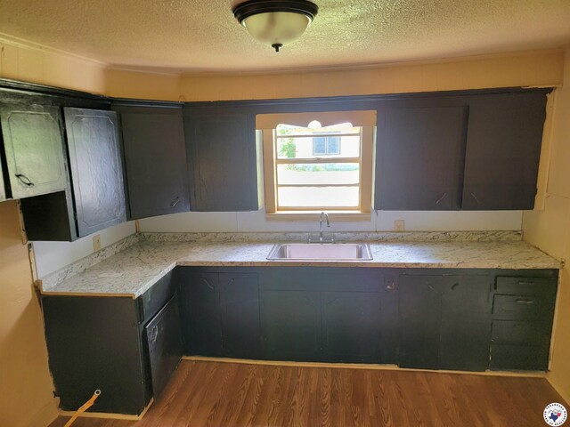 501 S Columbia St, Clarksville, TX 75426 - kitchen featuring a sink, a textured ceiling, wood finished floors, and light countertops
