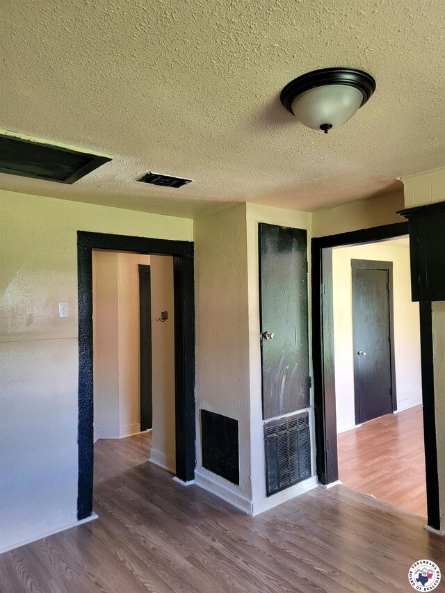501 S Columbia St, Clarksville, TX 75426 - unfurnished living room featuring a textured ceiling, a fireplace, and wood finished floors