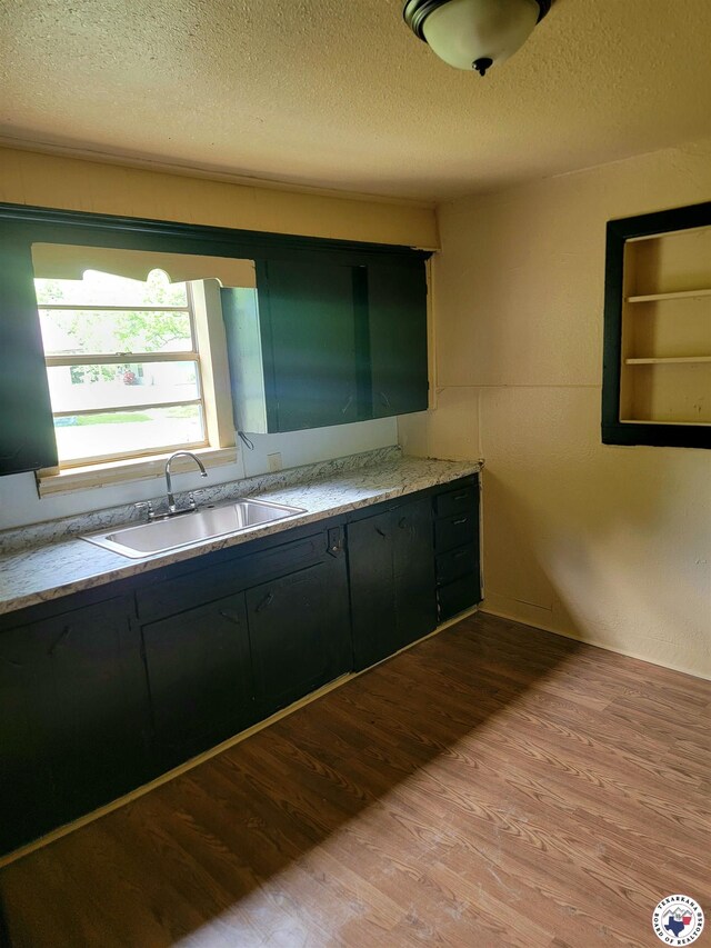 501 S Columbia St, Clarksville, TX 75426 - kitchen with a sink, a textured ceiling, light wood-style flooring, and light countertops