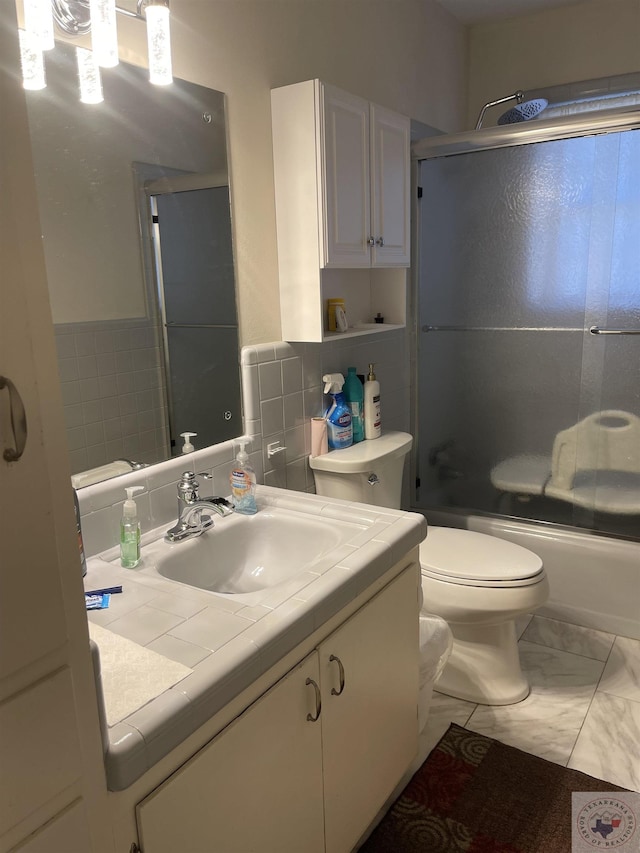 full bathroom with enclosed tub / shower combo, vanity, and toilet