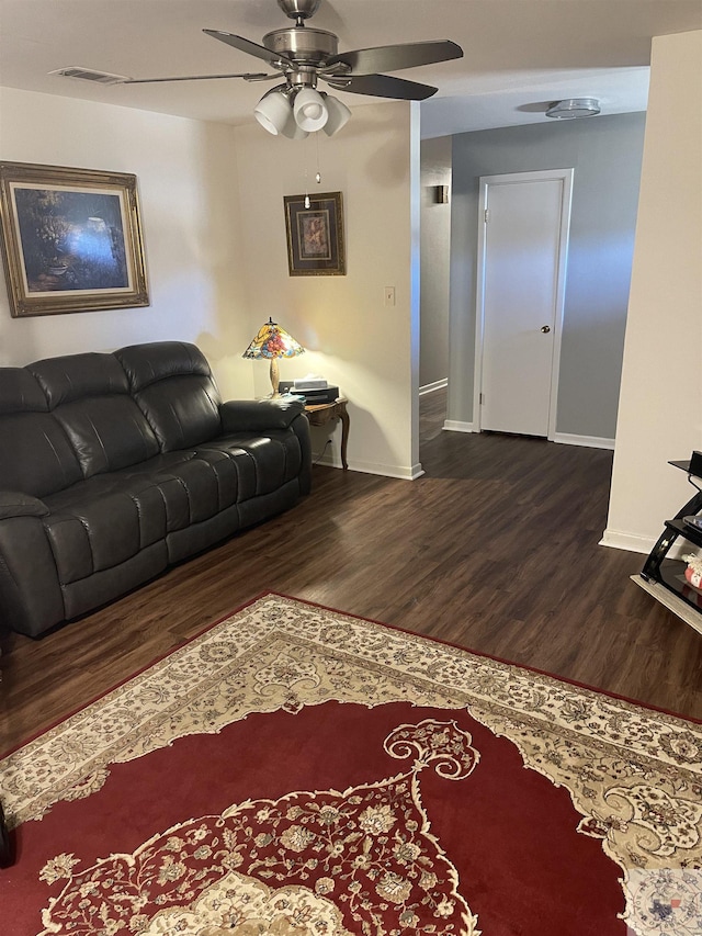 living room with ceiling fan and dark wood-type flooring