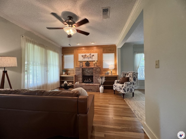 2504 Walnut St, Texarkana, TX 75503 - living room with a textured ceiling, a ceiling fan, wood finished floors, ornamental molding, and a brick fireplace