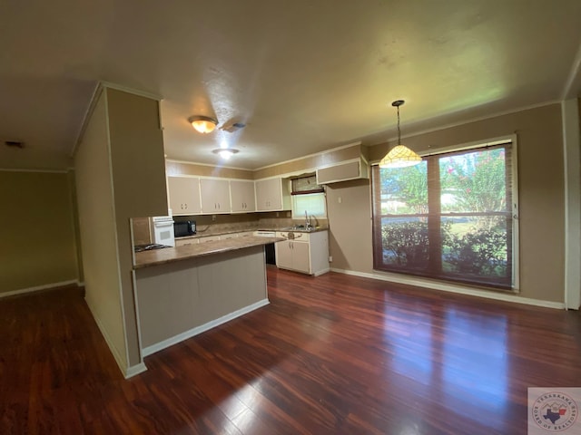 kitchen featuring kitchen peninsula, hanging light fixtures, dark hardwood / wood-style flooring, white cabinets, and ornamental molding