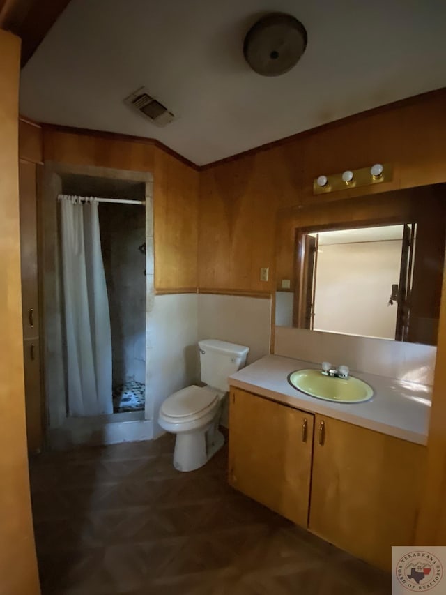 bathroom with a shower with curtain, wood walls, toilet, and vanity