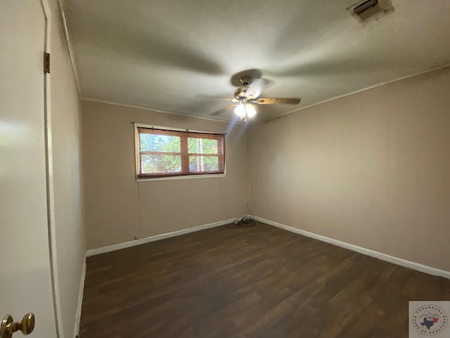 empty room with crown molding, dark wood-type flooring, and ceiling fan