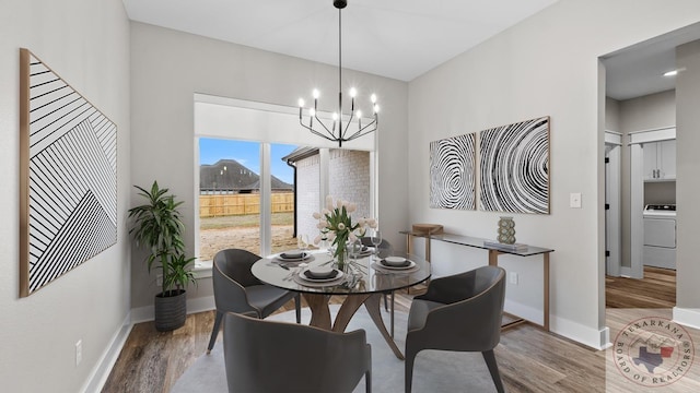 dining space with hardwood / wood-style flooring, washer / dryer, and an inviting chandelier