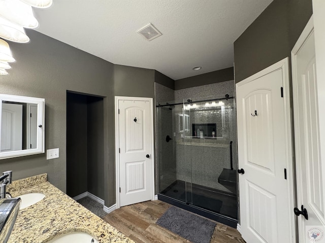 bathroom with vanity, hardwood / wood-style floors, an enclosed shower, and a textured ceiling