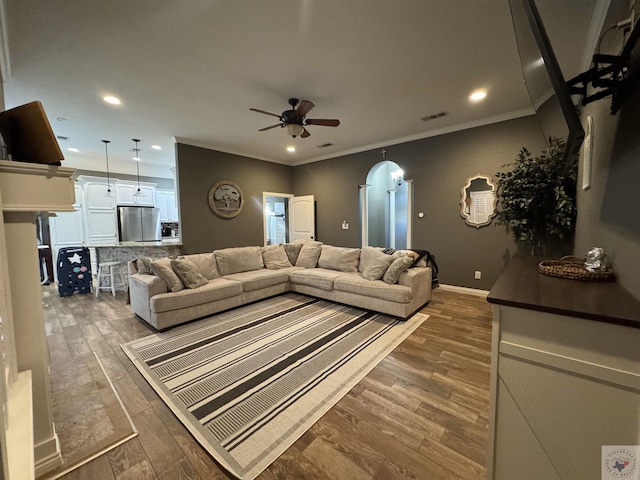 living room with dark hardwood / wood-style floors, ceiling fan, and ornamental molding