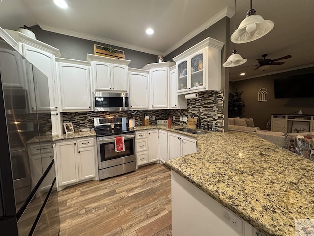 kitchen featuring kitchen peninsula, pendant lighting, white cabinetry, and stainless steel appliances