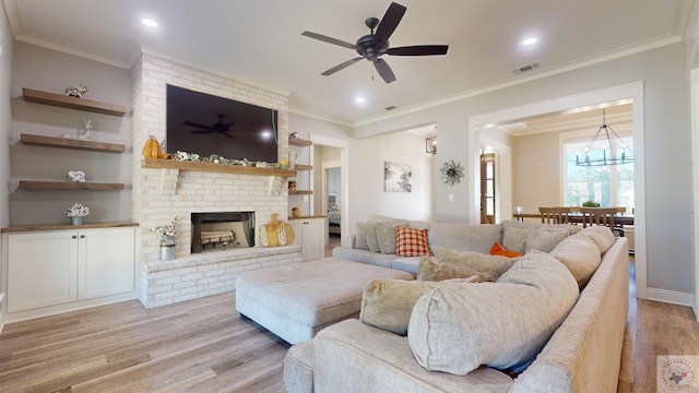 living room featuring ceiling fan with notable chandelier, ornamental molding, light hardwood / wood-style floors, and a fireplace