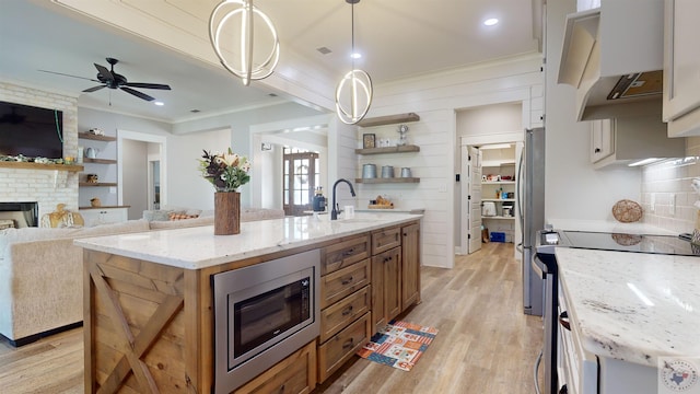 kitchen with a center island with sink, white cabinetry, hanging light fixtures, and stainless steel appliances