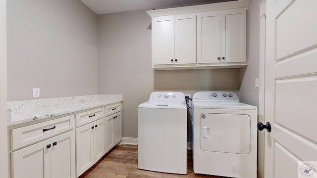 laundry room featuring cabinets, light wood-type flooring, and washer and dryer