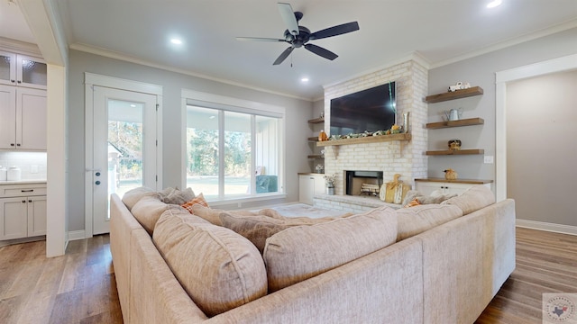 living room with hardwood / wood-style flooring, a brick fireplace, crown molding, and ceiling fan