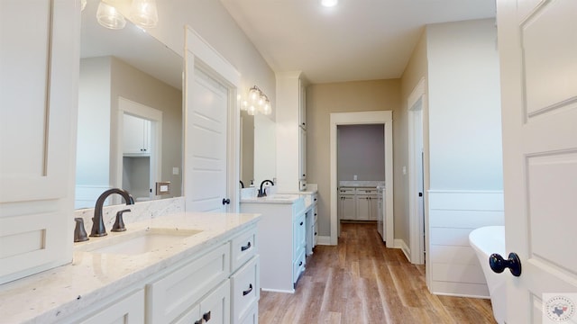 bathroom with hardwood / wood-style flooring, a tub, and vanity