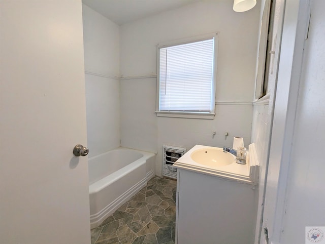 bathroom with tile walls, a bathtub, heating unit, and vanity