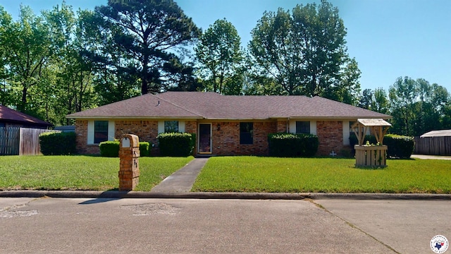 ranch-style house with a front yard, fence, and brick siding