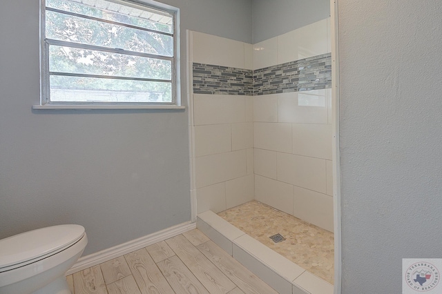 bathroom featuring a tile shower, wood-type flooring, and toilet