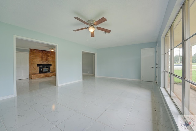 spare room with a fireplace and ceiling fan