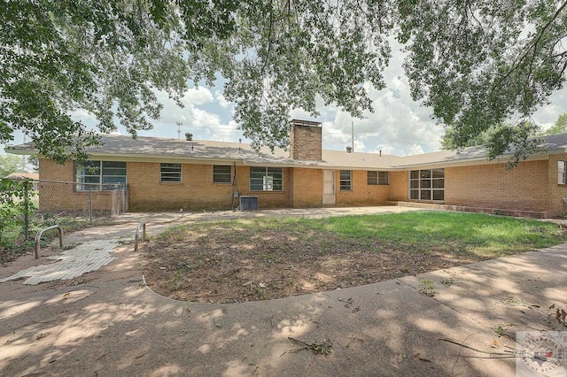 rear view of property with central AC unit and a lawn