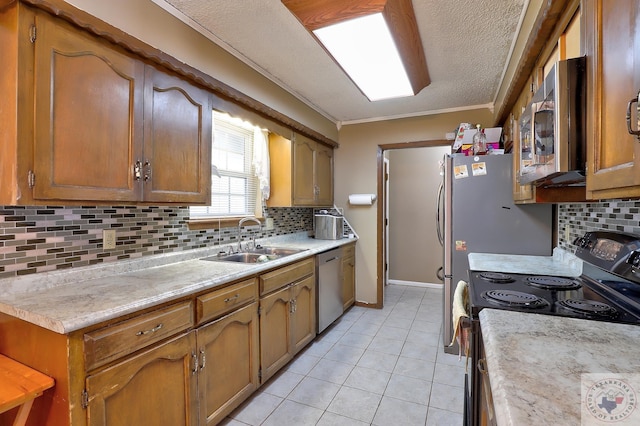 kitchen with light tile patterned flooring, a sink, light countertops, appliances with stainless steel finishes, and brown cabinetry